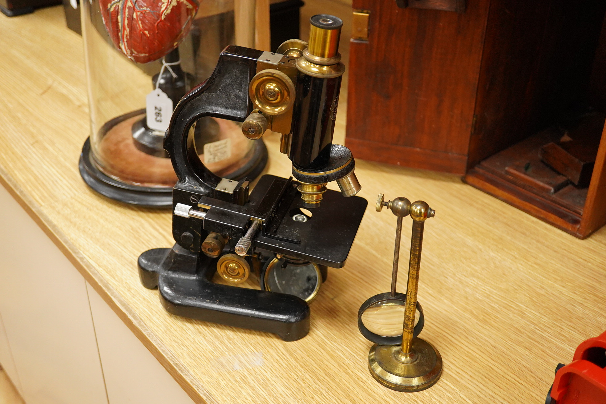 An early 20th century pine and plywood cased microscope by C.Baker, London, containing an integral drawer with alternative lenses, and a magnifying glass on a brass stand, the case dimensions; 38cm high, 18cm wide, 27.5c